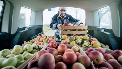 Man tilt appels in zijn bedrijfswagen die hij zakelijk least 