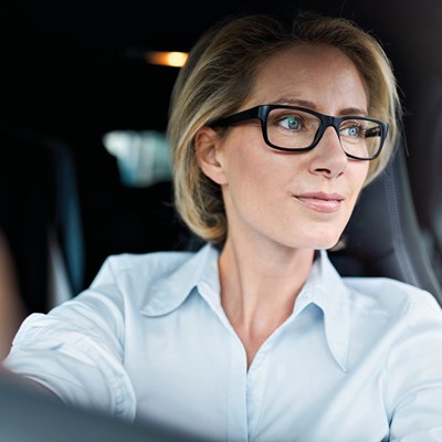 Business woman with glasses behind the wheel