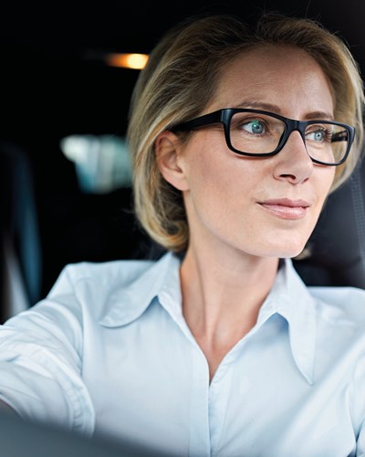 Business woman with glasses behind the wheel