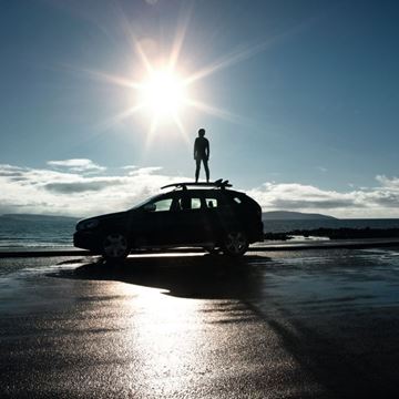 Perfil de una persona sobre un vehículo se recorta frente al sol 