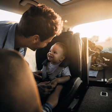 Padre abrocha a su bebé en la silla de coche homologada