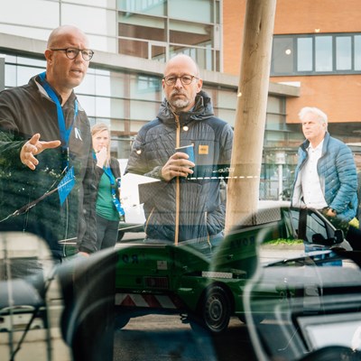 Mannen in gesprek bij een elektrische bedrijfswagen
