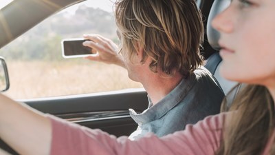 Young Couple On Holiday In Car Taking A Picture